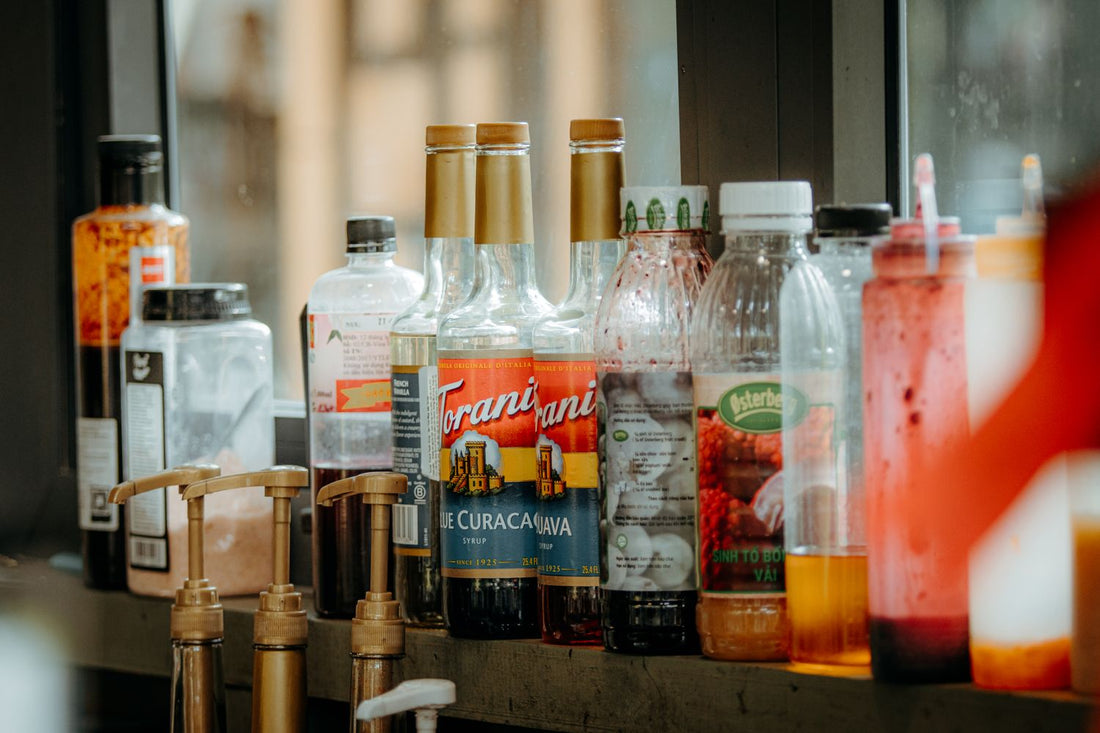 Verschillende flessen met siroop op een bar in een cafésetting