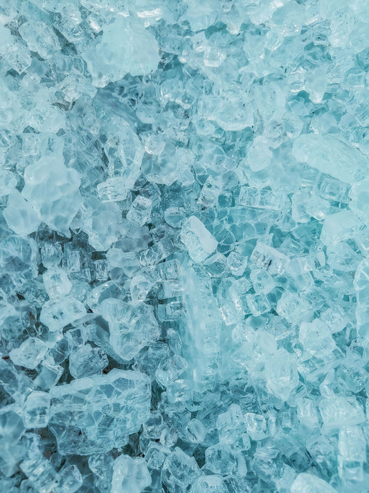 Close-up van fijn gebroken crushed ice met een blauwe glans, zoals gebruikt in cocktails