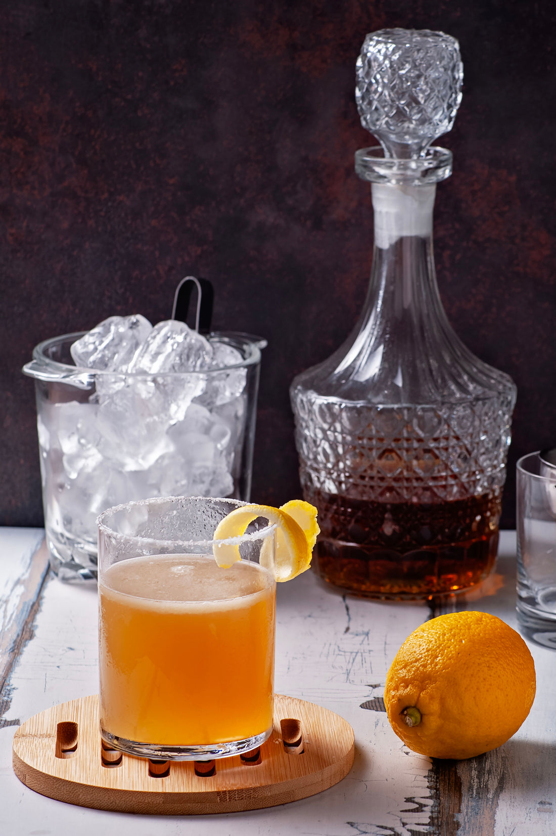 Whiskey sour in een glas met een schijfje citroen en ijs op een donkere bar