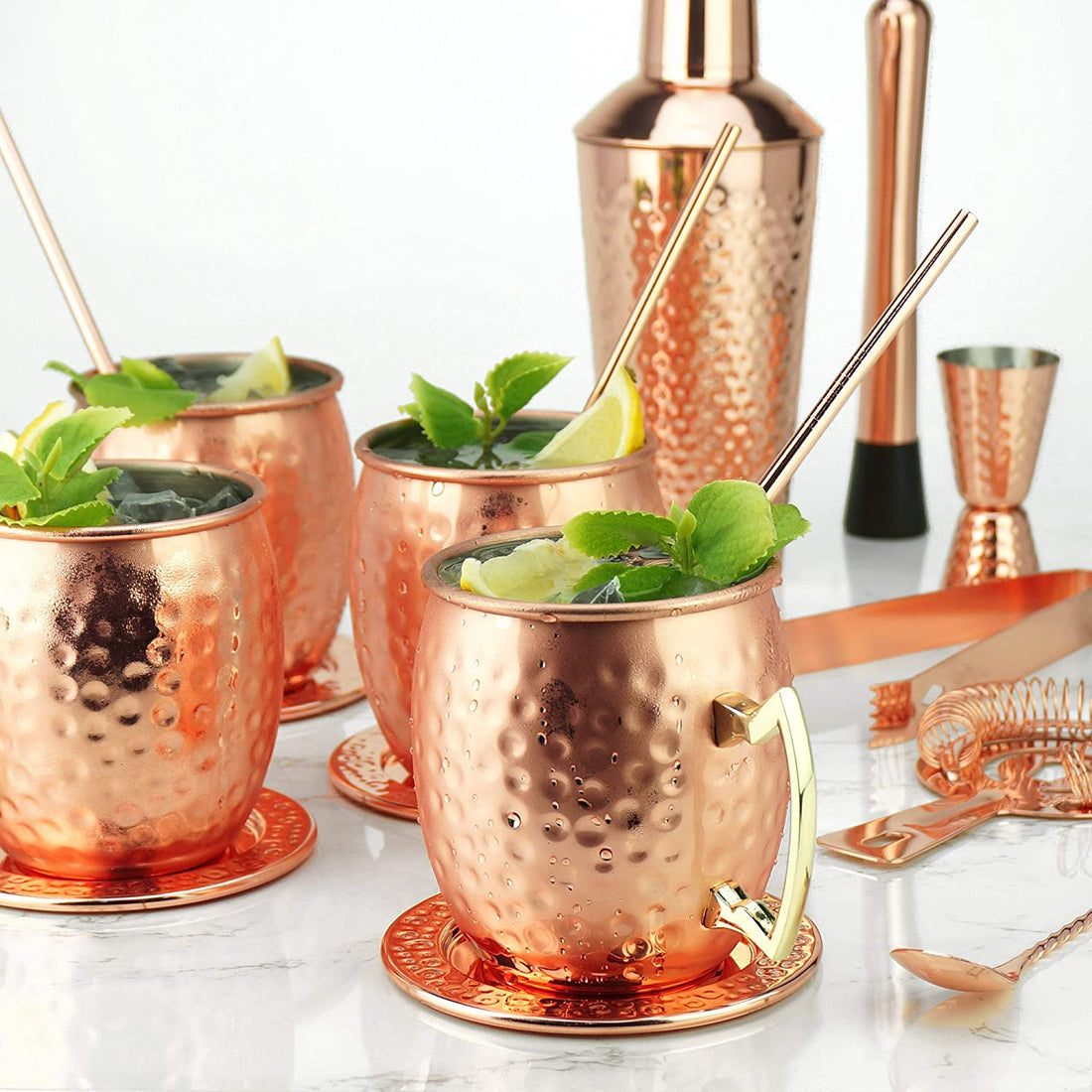 Moscow Mule in een koperen beker met limoen, munt en ijs, naast een Sybra cocktailset