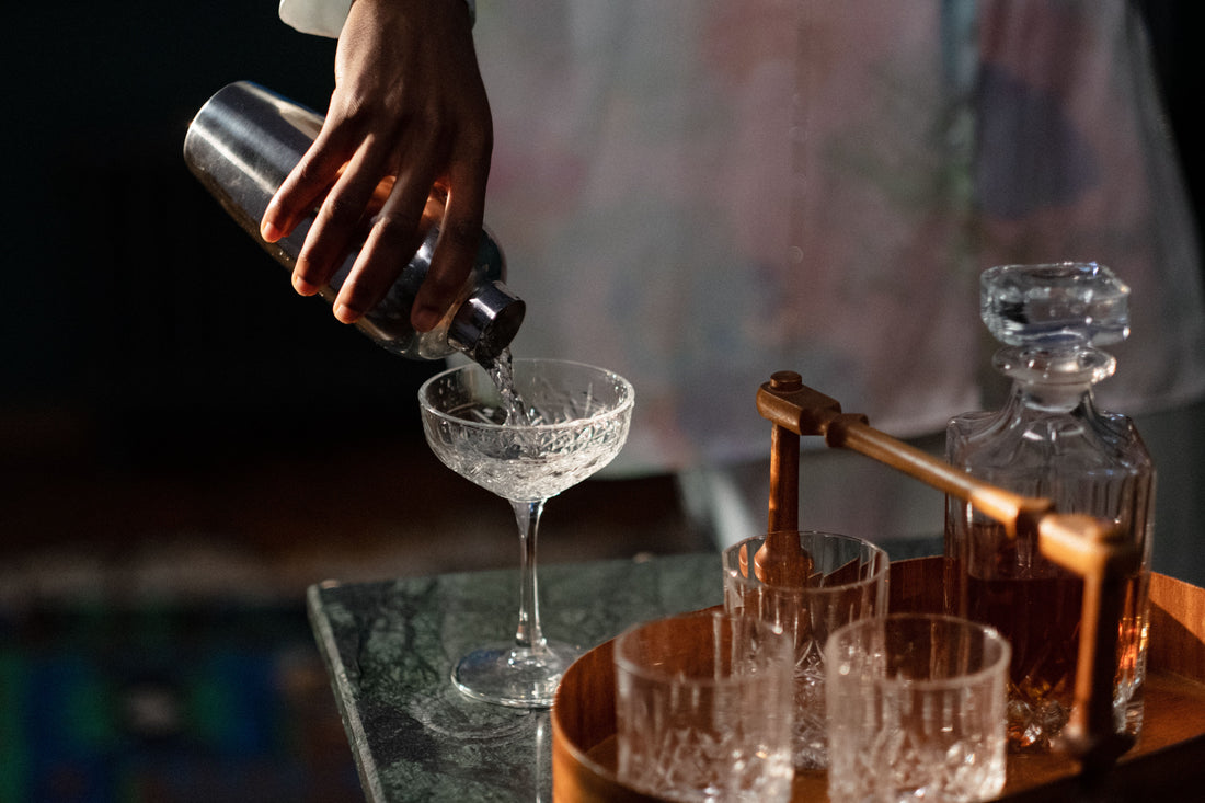 Hand giet een cocktail uit een metalen shaker in een glas