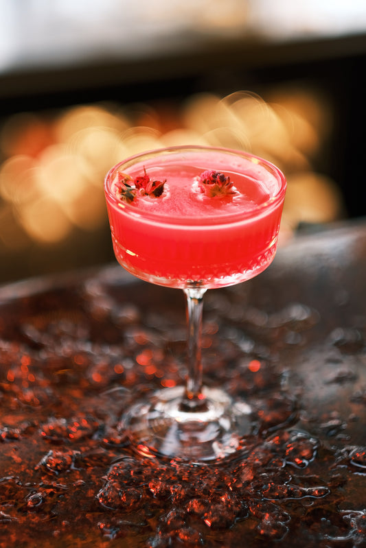 Rode cocktail in een glas met bessen als garnering op een barblad