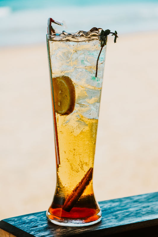 Long Island Iced Tea in een hoog longdrinkglas met ijs, een schijfje citroen en een rietje, met de kenmerkende ijstheekleur.