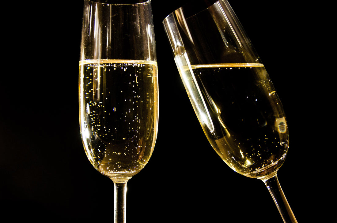 Close-up van hoge champagneglazen met bruisende wijn en fijne belletjes tegen een donkere achtergrond