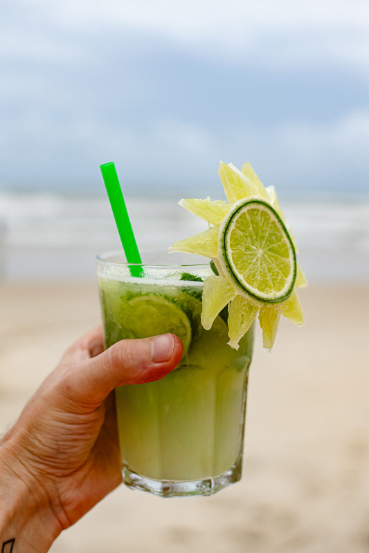 Caipirinha cocktail met limoen en ijs geserveerd in een laag glas op een zonnig strandterras