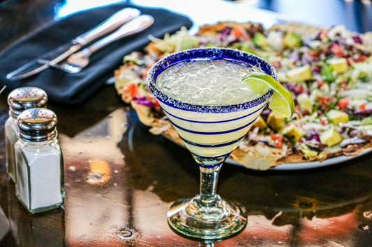 Margarita cocktail met zoutrand en een partje limoen in een cocktailglas op tafel