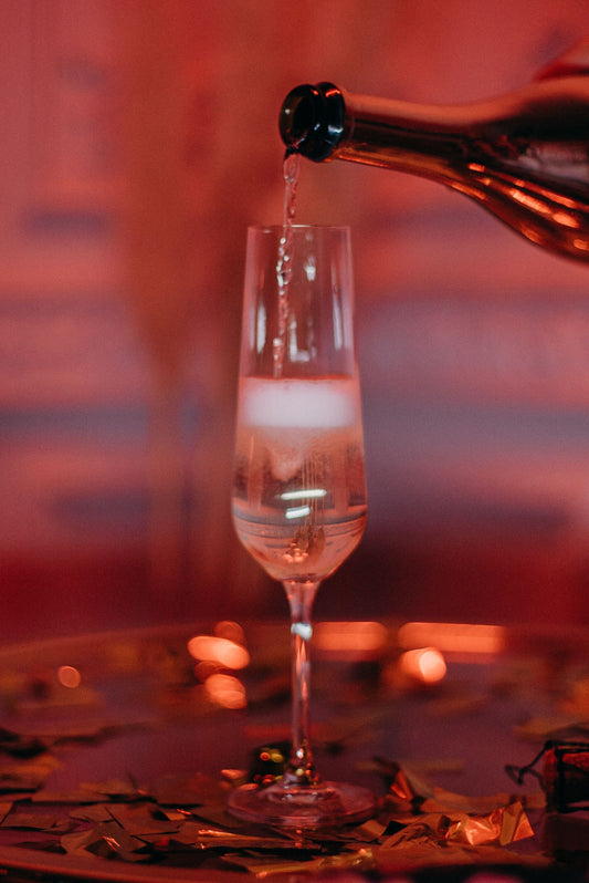 Close-up van bruisende champagne die in een slank flûte-glas wordt geschonken voor een French 75 cocktail