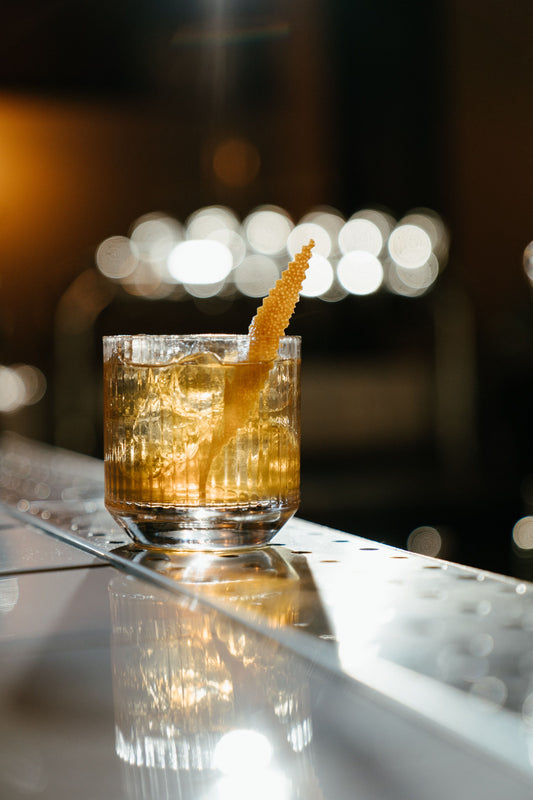 Whiskey Sour in een tumbler met ijsblokjes en een citrusgarnering op een bar