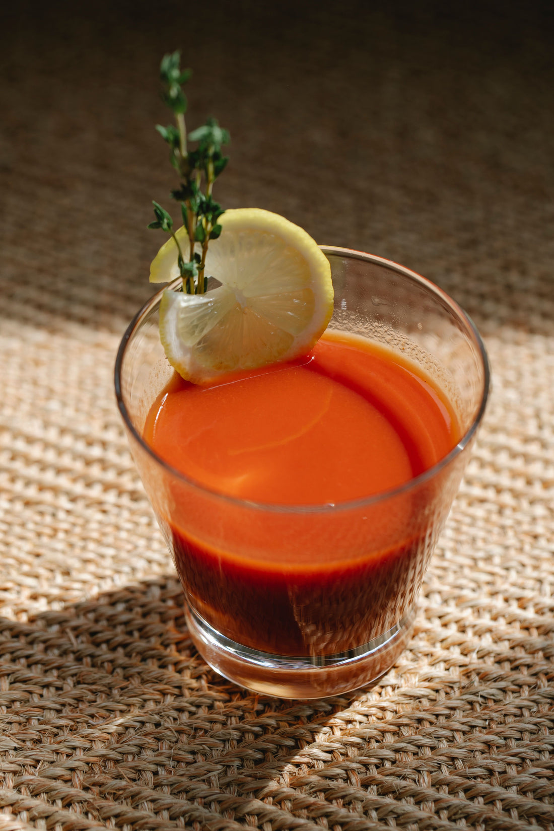 Bloody Mary cocktail met tomatensap, geserveerd in een hoog glas met een schijfje limoen en een takje tijm