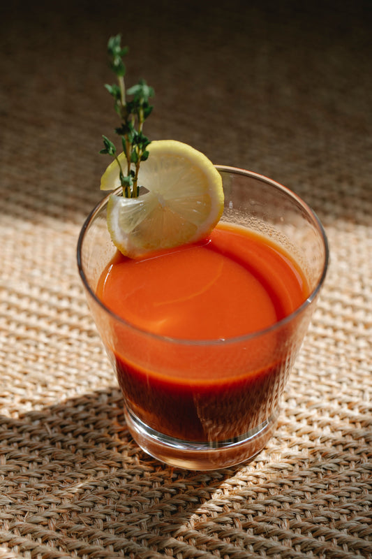 Bloody Mary cocktail met tomatensap, geserveerd in een hoog glas met een schijfje limoen en een takje tijm