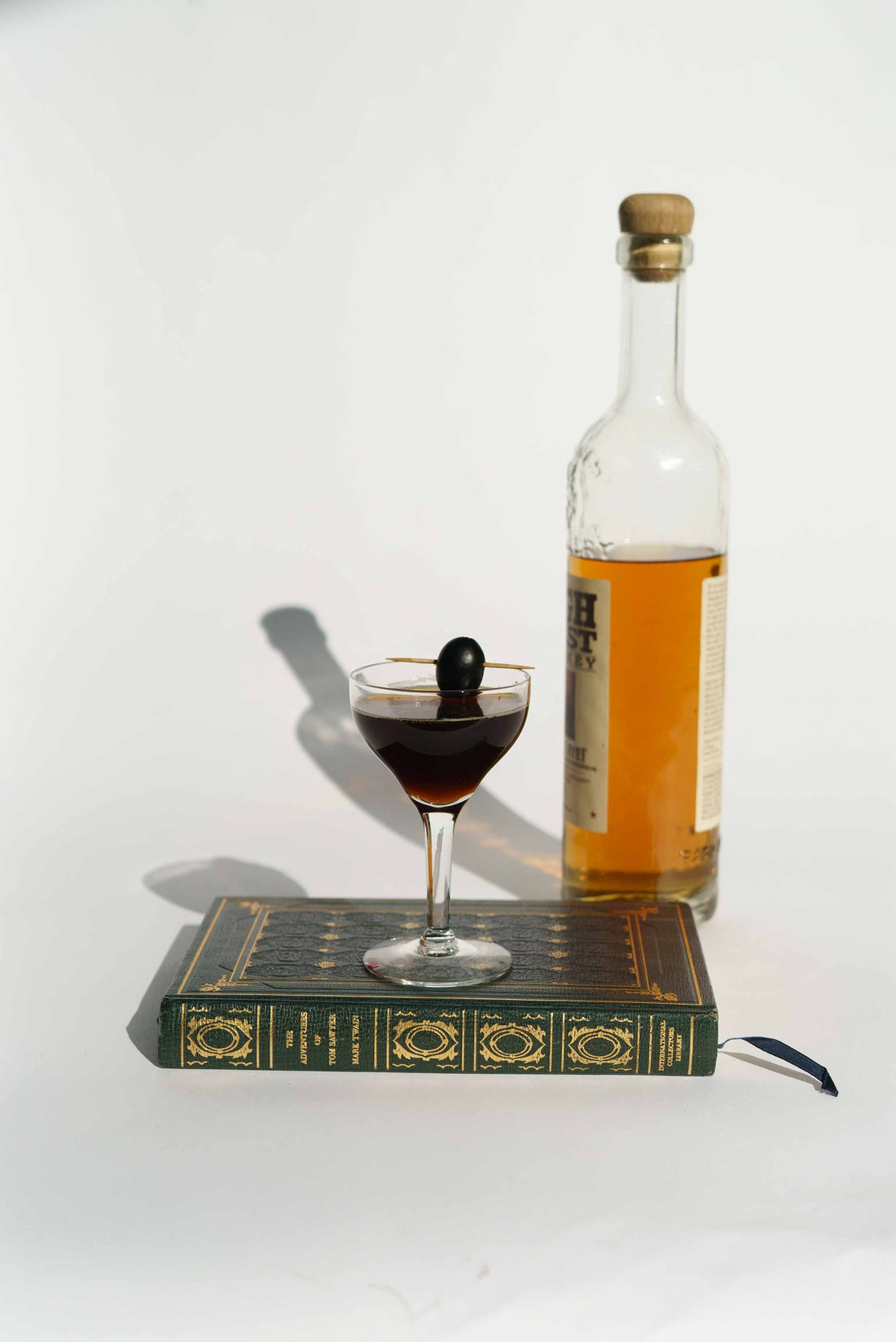 Manhattan cocktail in een klassiek cocktailglas naast een fles whiskey