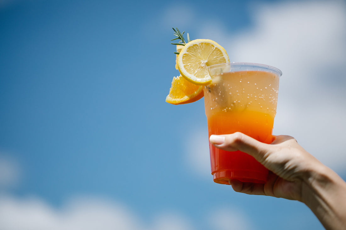Tequila Sunrise cocktail met oranje-rood kleurverloop en schijfjes citrus tegen een blauwe lucht