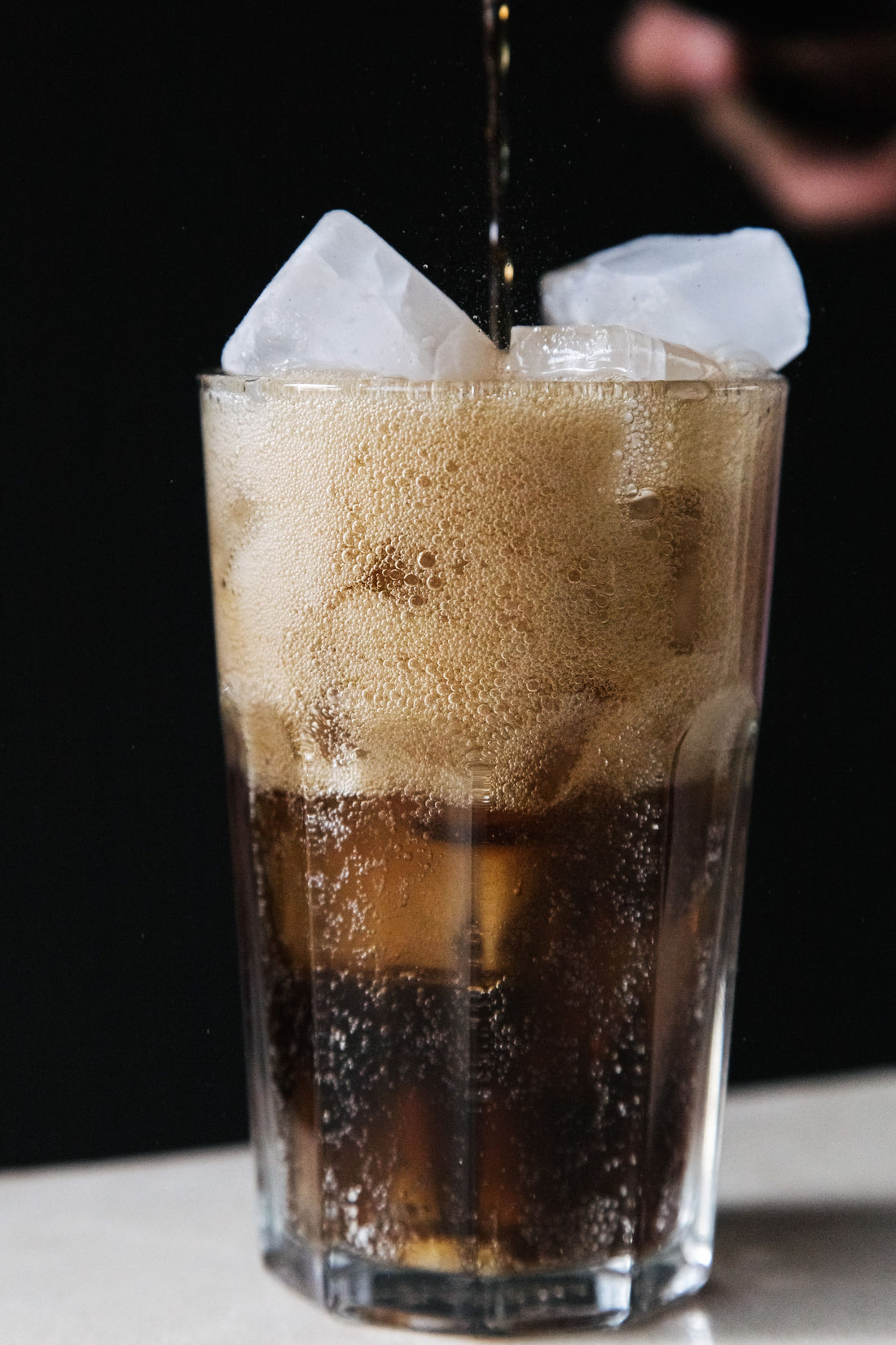 Piscola cocktail met cola en ijsblokjes in een longdrinkglas