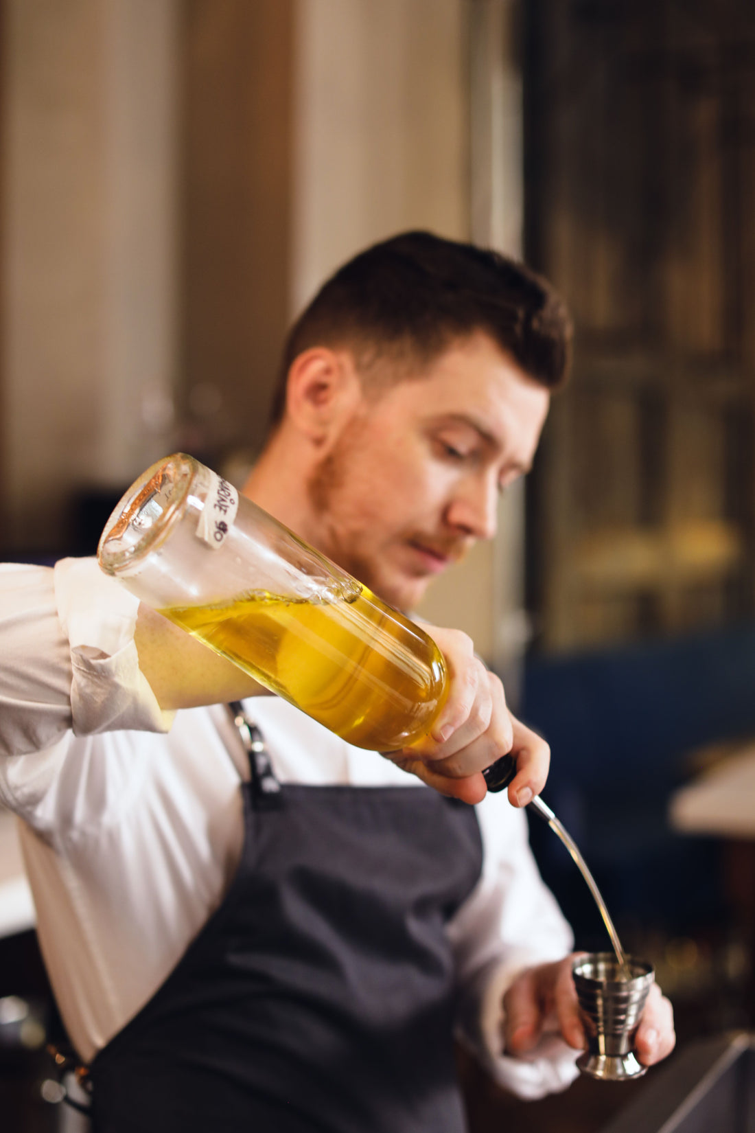 Iemand schenkt sterke drank af met een jigger om de juiste cocktailverhoudingen te meten